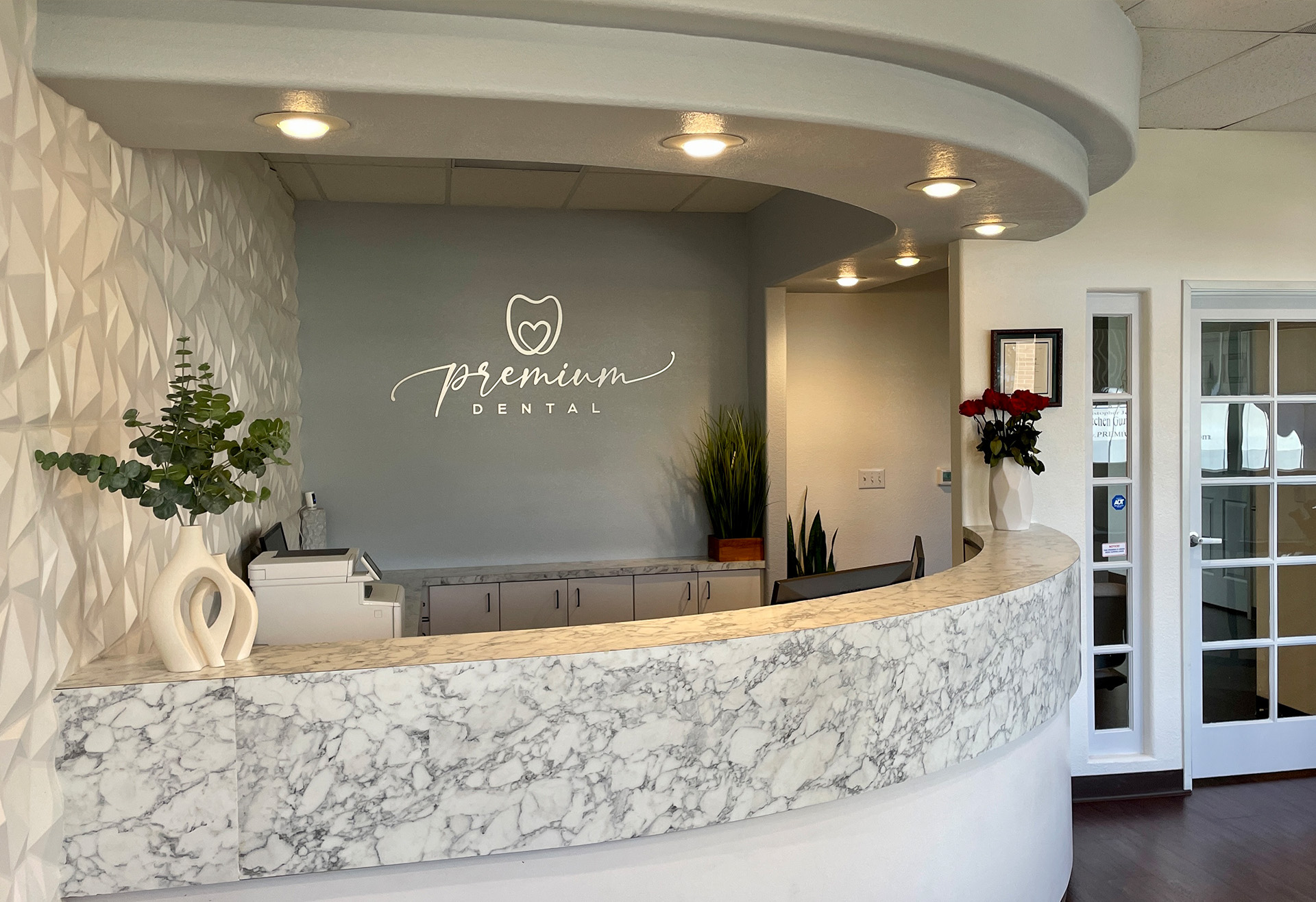 The image shows a modern dental office reception area with a marble countertop and a sign that reads  Premium Dental.