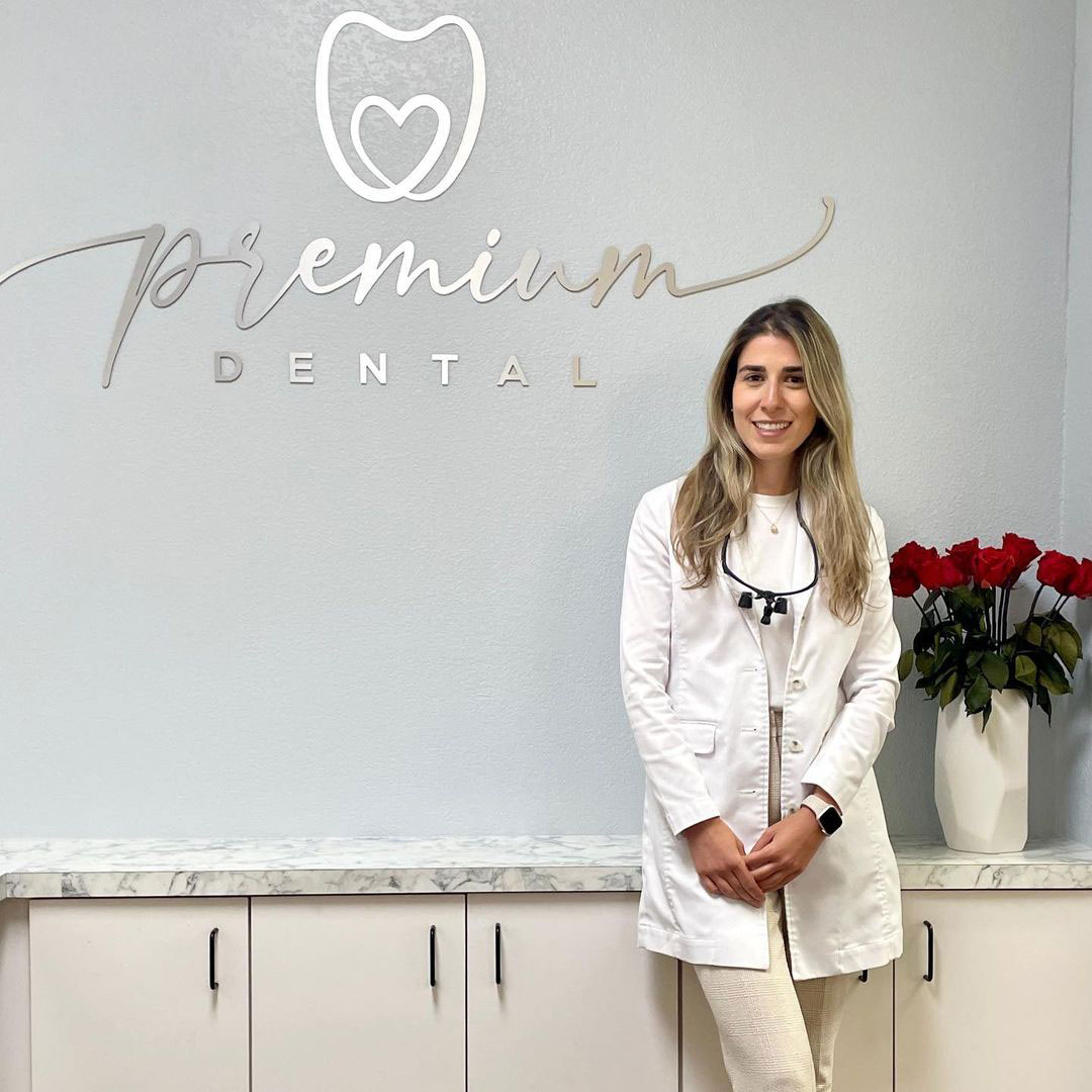 A woman standing in front of a dental office sign.