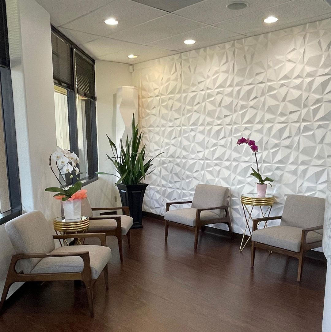Waiting room with modern furniture, a wall-mounted plant, and decorative elements.