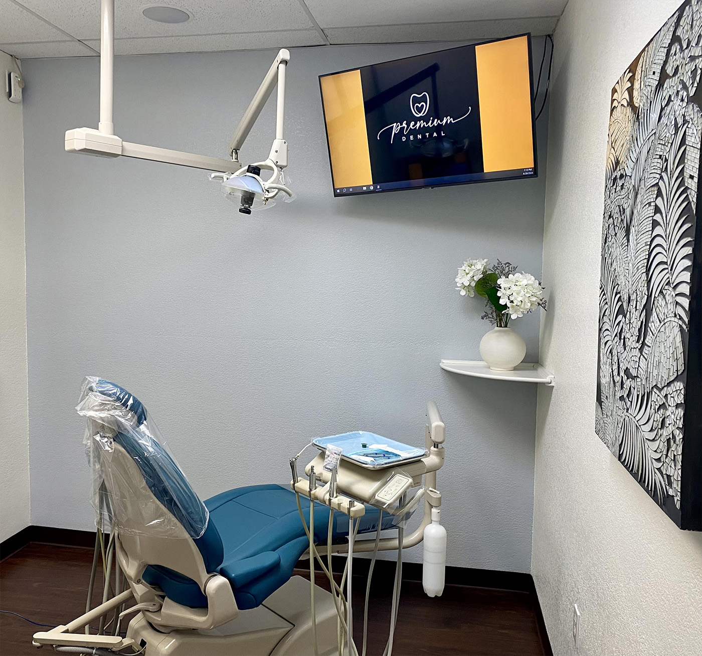 An image of a dental office interior with a chair, dental equipment, and a television screen displaying the word  Premium .