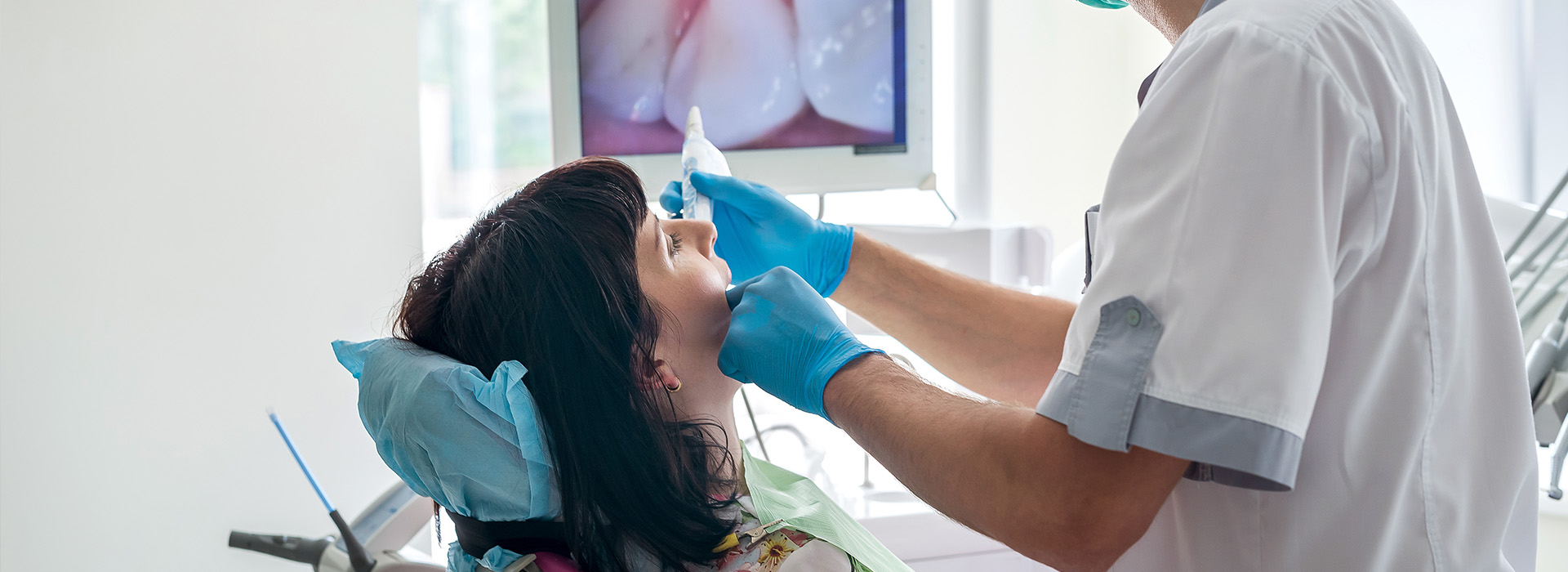 A dental hygienist is performing a cleaning procedure on a patient s teeth, using a dental drill and wearing protective eyewear.