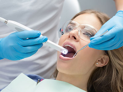 The image shows a dental hygiene professional using an electric toothbrush to clean a patient s teeth during a dental appointment.